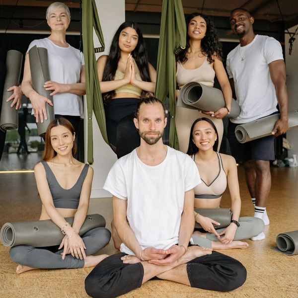 Diverse group of people smiling during a yoga class in a bright studio.